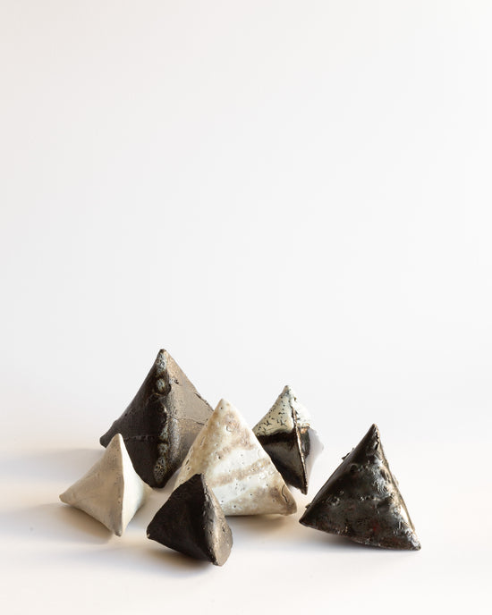 Set of six ceramic curved triangular objects in different sizes, glazed in black and white