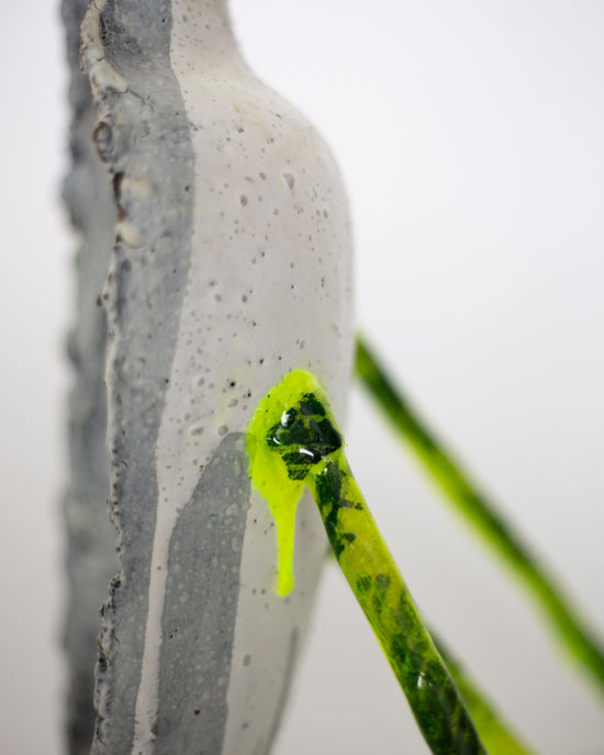 Close-up of a half ceramic vessel in white, supported by three fluorescent yellow stands
